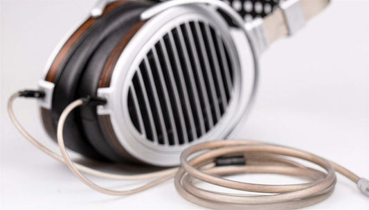 Pair of HE1000se headphones with stock cable on a light background